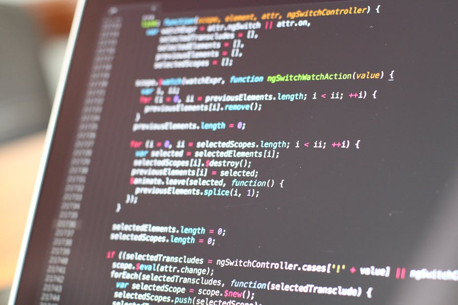 A close-up view of a person's hands typing on a laptop keyboard, with the screen displaying lines of code in a dark-themed text editor. The laptop is positioned on a black surface, and the background 